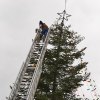Volunteer fireman Nick Reed adjusts lights at the top of the tree.