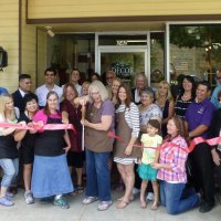 Lynda Lahodny cuts the ribbon in front of her store as friends watch.