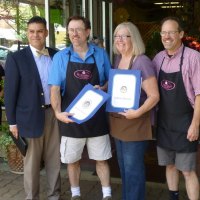 Ramblin' Rose owners Chris Brazil and John Miller join Lynda Lahodny in receiving a State Legislature proclamation on Thursday during the stores' ribbon cuttings.