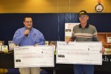 National Rifle Association representative Paul Rodarmel presents checks to Richard Lehn of the Lemoore Hot Shots, a local group that fires pellet guns at an indoor range at the Lemoore Rec Center.