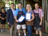 Ramblin' Rose owners Chris Brazil and John Miller join Lynda Lahodny in receiving a State Legislature proclamation on Thursday during the stores' ribbon cuttings.