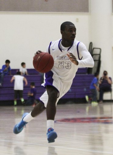 Roger Wilson brings the ball up court for Tigers.